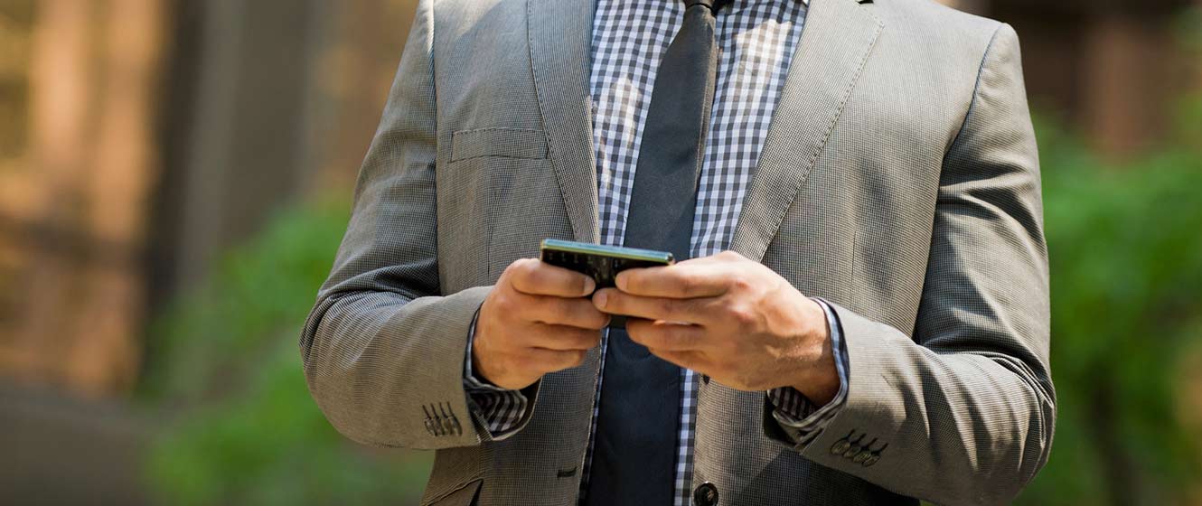 Image of a man in business suit using phone banking on his smart phone, outside.