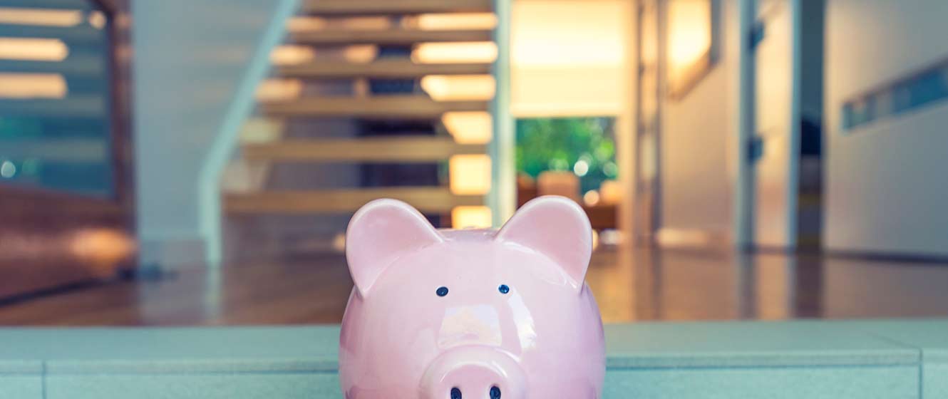 Image of piggy bank in front of house interior.