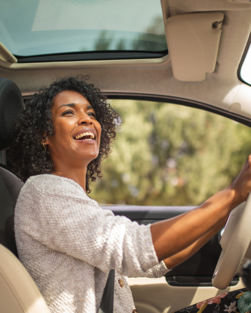 Smiling young African American woman driving in her car