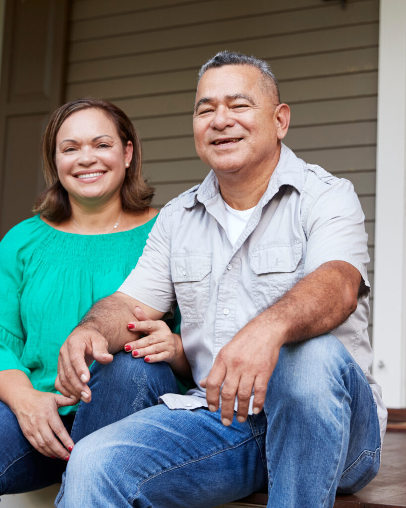 Smiling couple sitting on the front steps of their home