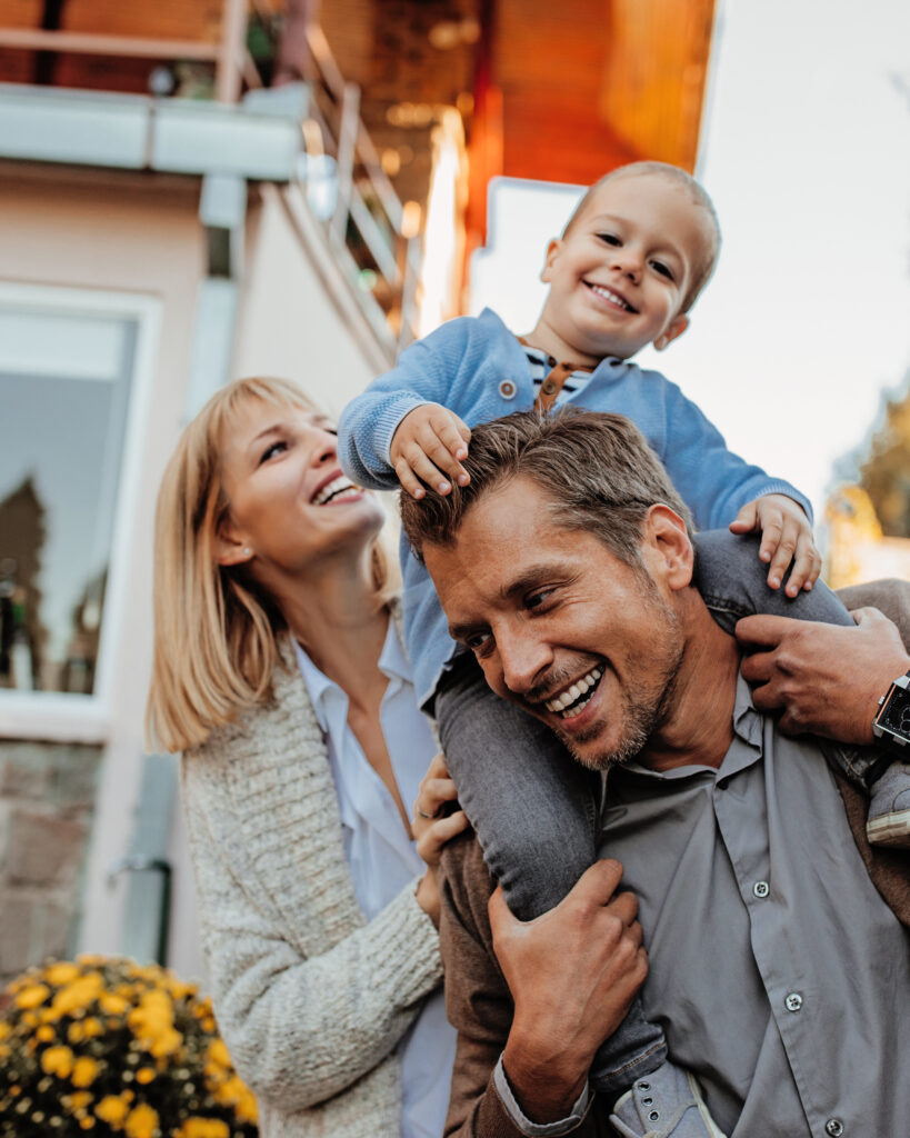 Smiling family outside their house